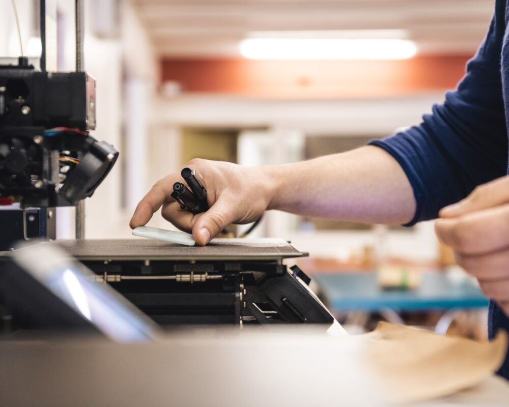 Photo d'une imprimante 3D en gros plan pour illustrer le travail de l'atelier.