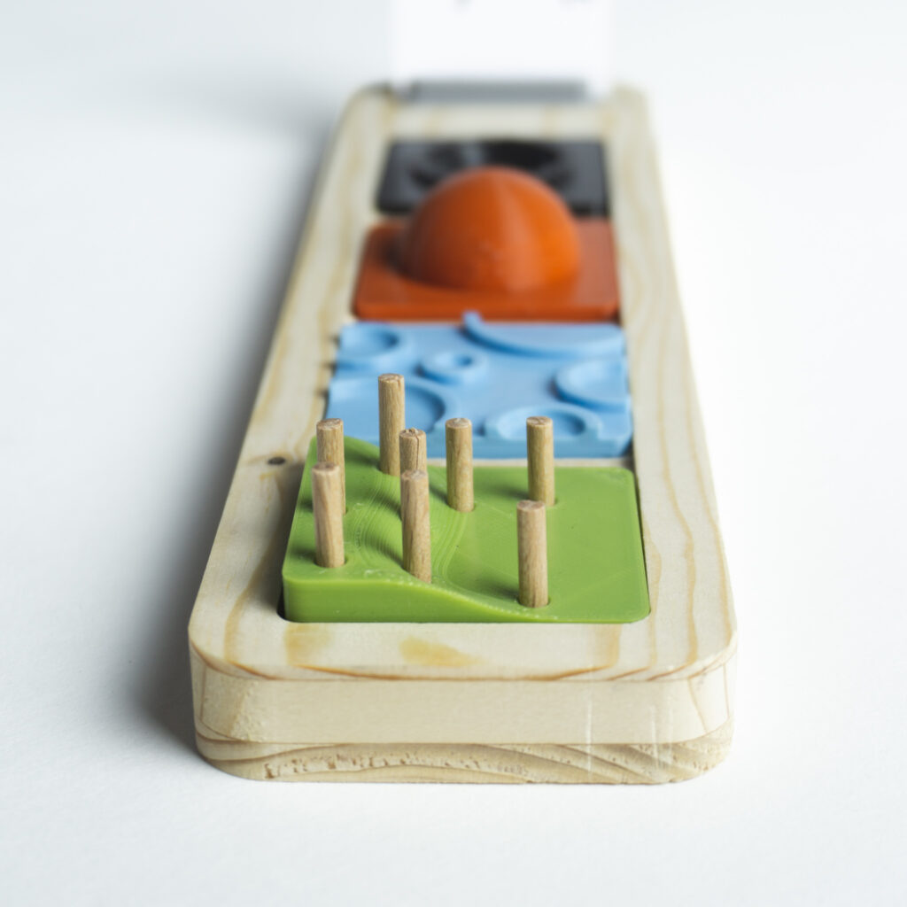 Zoom sur un outil ludique composé de pièces imprimées en 3D et d'un socle en bois découpé. Les pièces sont interchangeables et permettent aux utilisateurs de tester des configuration différentes.