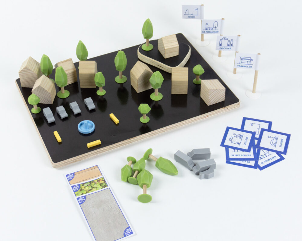 Maquette ludique d'urbanisme composée de maisons en bois, d'arbres imprimés en 3D et de cartes pour identifier et placer des usages.